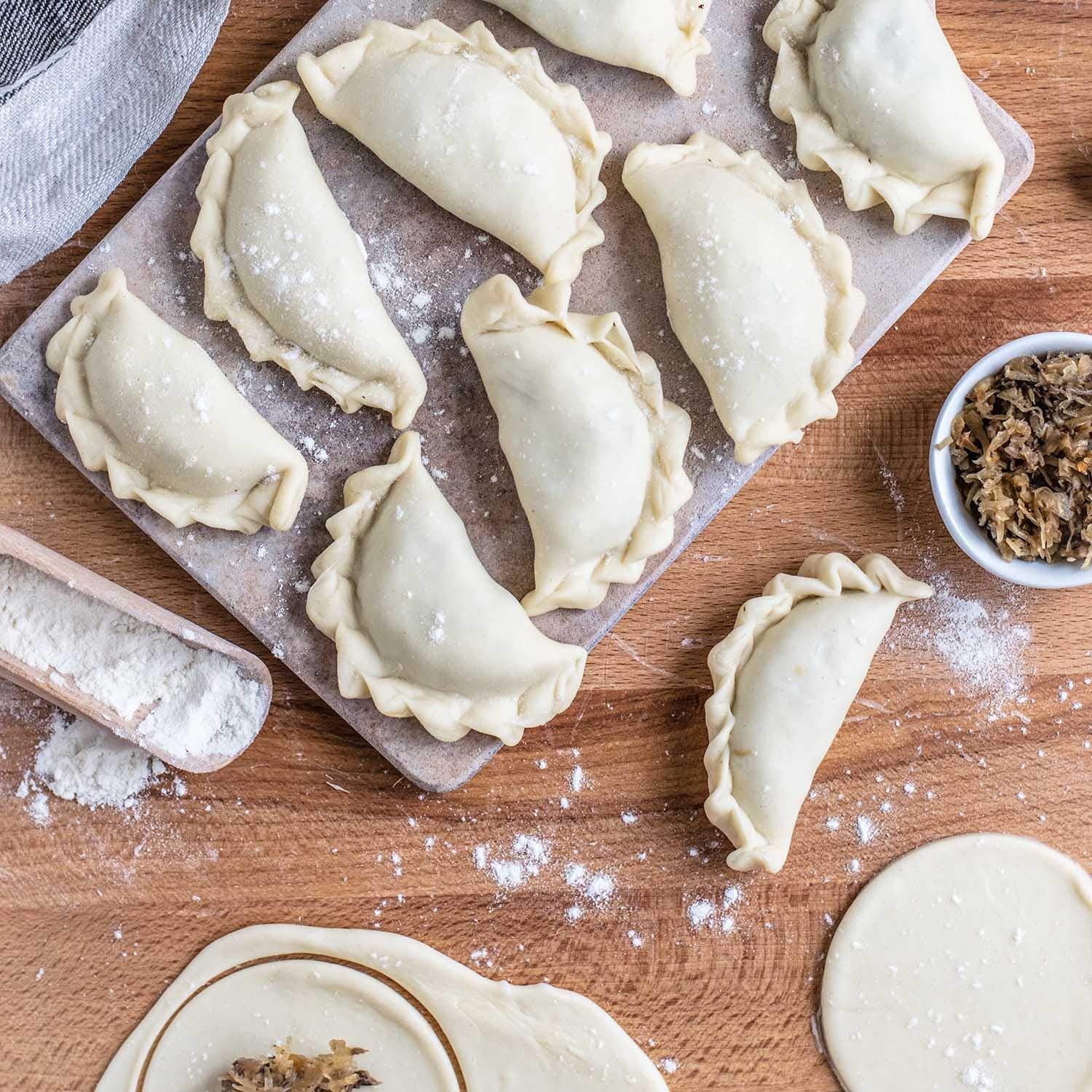 Fresh dumplings and wrappers on a floured wooden board