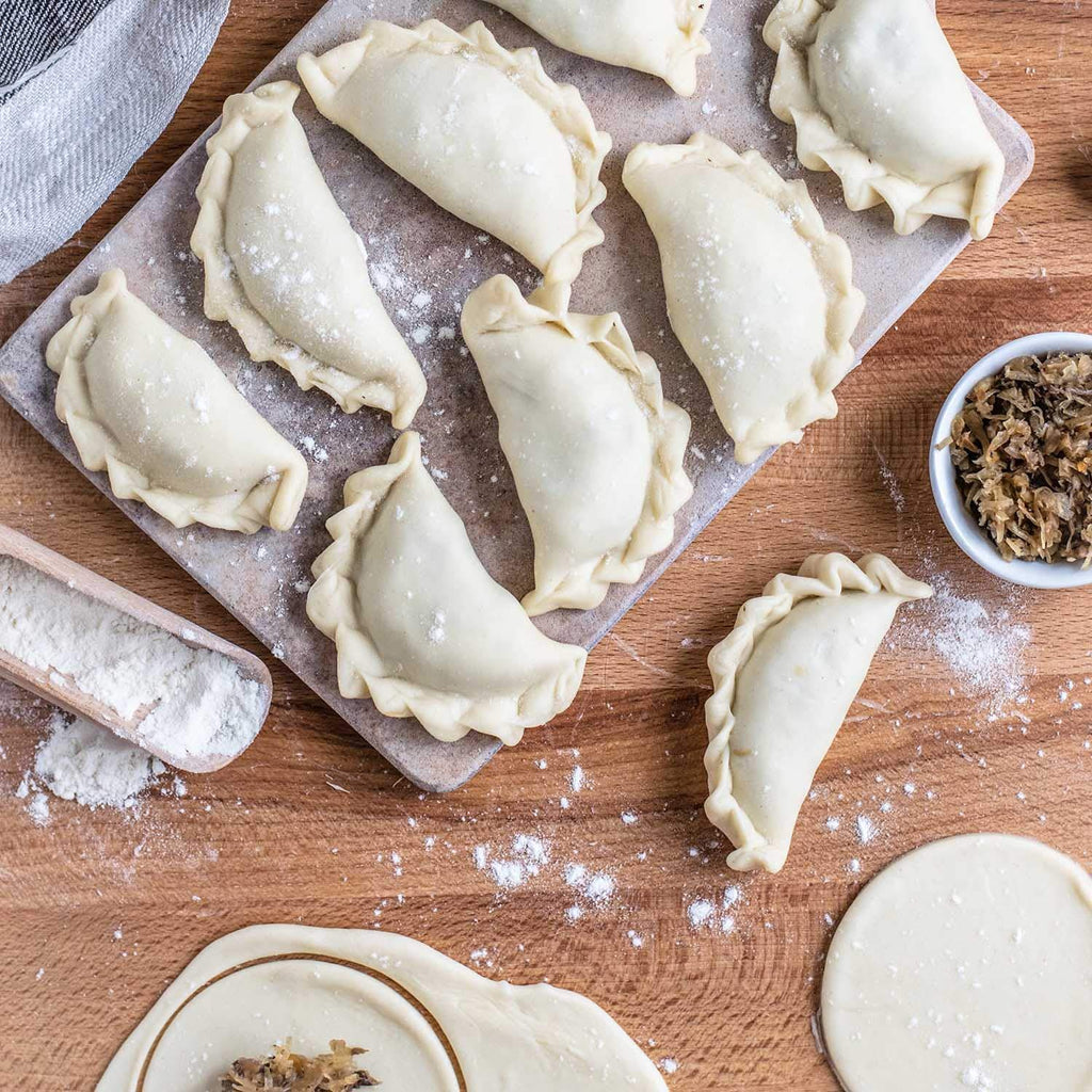 Fresh dumplings and wrappers on a floured wooden board